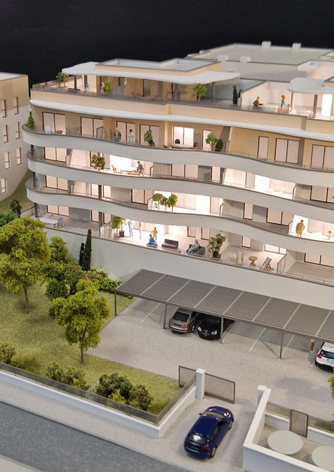 Maquette illuminée de la résidence "Azuréa" à Romans-sur-Isère : immeubles aux lignes courbes blanches et fluides, dotés de vastes terrasses en gradins et balcons, implantés dans un parc arboré avec stationnement paysager.