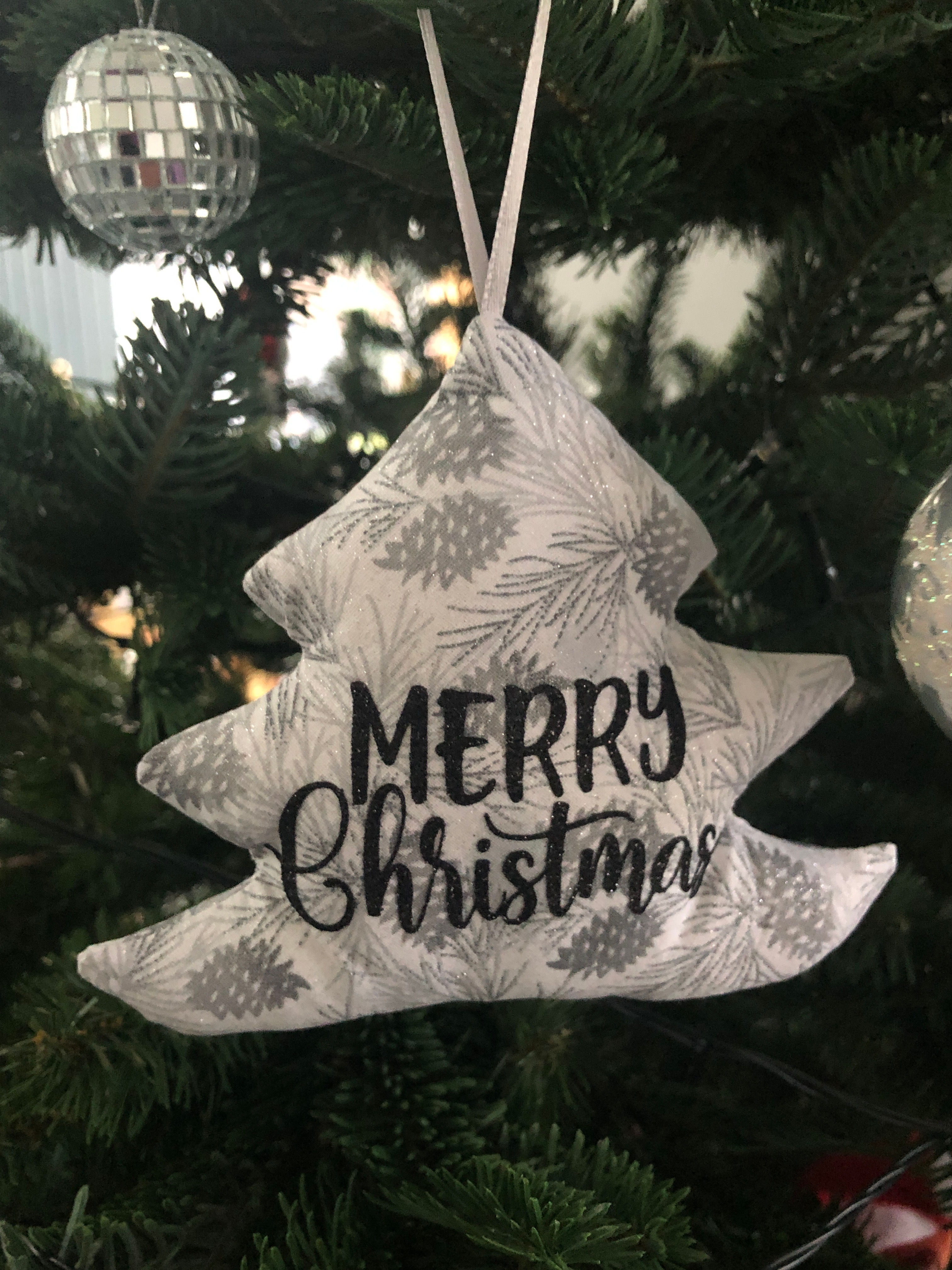 Sparkly silver Pine cones and Fir branch fabric in a Christmas tree shaped bauble with Merry Christmas in Black font