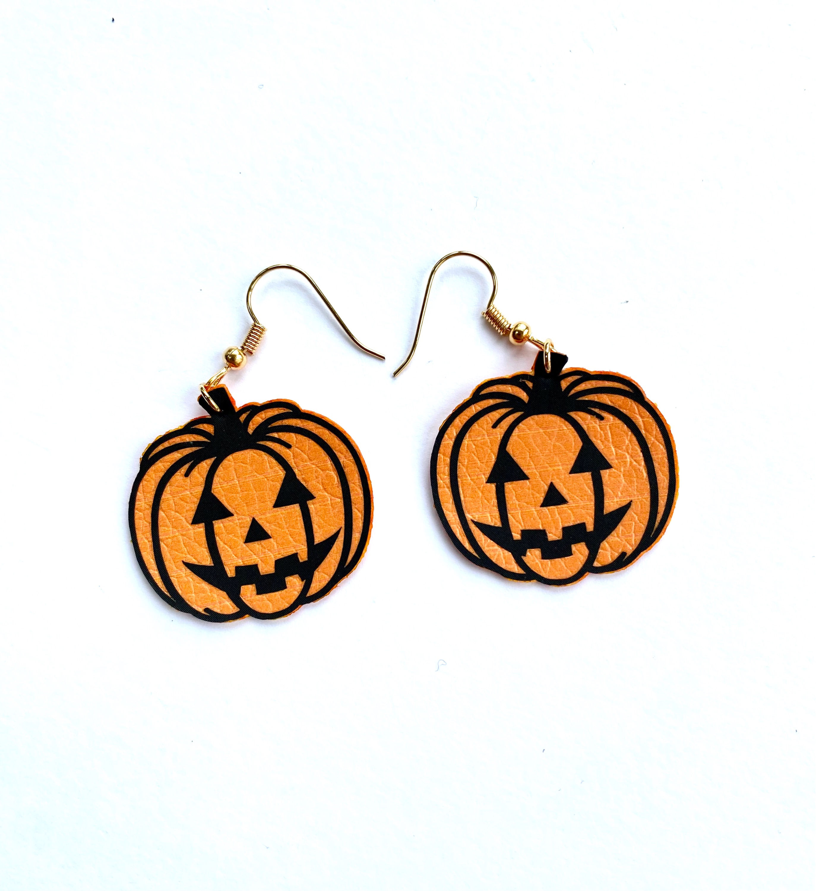 Carved pumpkin earrings showing the face and segments in black