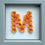 Thumbnail: Rolled Orange Paper Flowers on a white glitter background in a grey frame