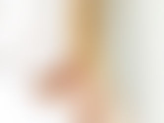 Woman in a towel and robe looking at her skin in the mirror during a self-care routine.