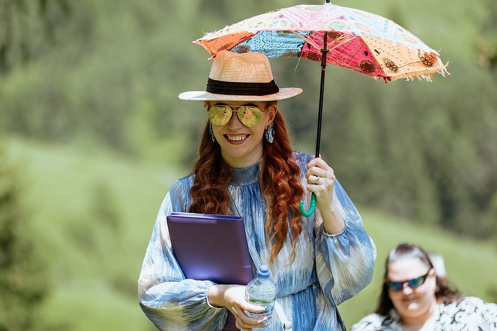 Katie the wedding celebrant armed with a parasol, hat, sunglasses and water, ready for a scorching outdoor ceremony.