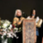 two people on a stage in front of a podium, appearing to be singing