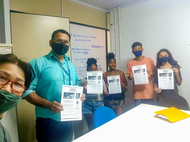 6 people are shown, four of which are youth, two are the facilitator, all of them are holding up a sheet of paper with information regarding the clean-up