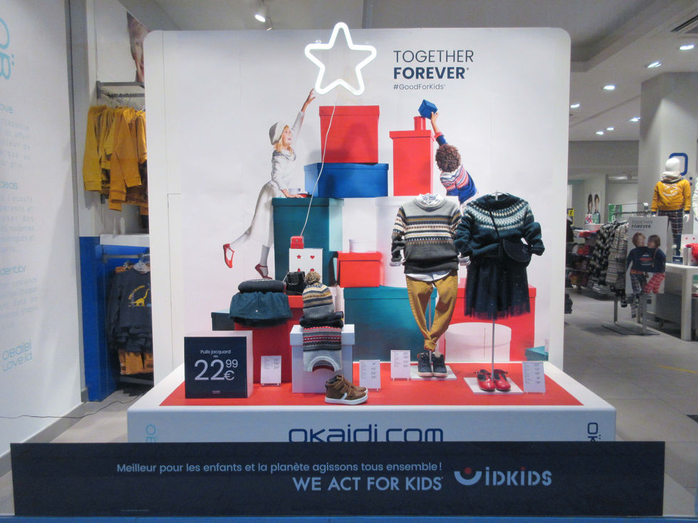 Scénographie de vitrine de Noël Okaïdi avec un empilement créatif de boîtes en carton de différentes dimensions.