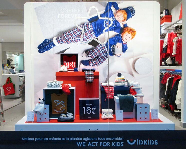 Scénographie de vitrine de Noël Okaïdi avec un empilement créatif de boîtes en carton de différentes dimensions.