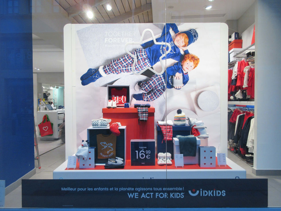 Scénographie de vitrine de Noël Okaïdi avec un empilement créatif de boîtes en carton de différentes dimensions.