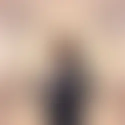 une avocate brune en robe dans son bureau une tablette à la main et des collegues à leur bureau