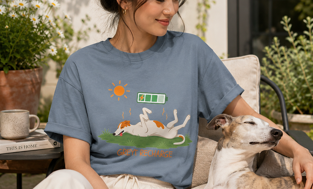 Person wearing an original studio animal graphic tee while relaxing with a whippet outdoors, representing the Original Studio Tees collection.