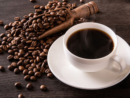 coffee inside cup and coffee beans on top of table
