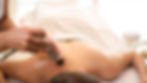 A woman receiving shockwave therapy with a handheld device, promoting relaxation and muscle recovery during her massage session.