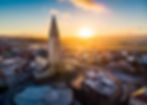 Aerial view of a tall church in Reykjavik with a pointed tower in a snowy city at sunrise. Warm light and vibrant colors create a serene atmosphere.