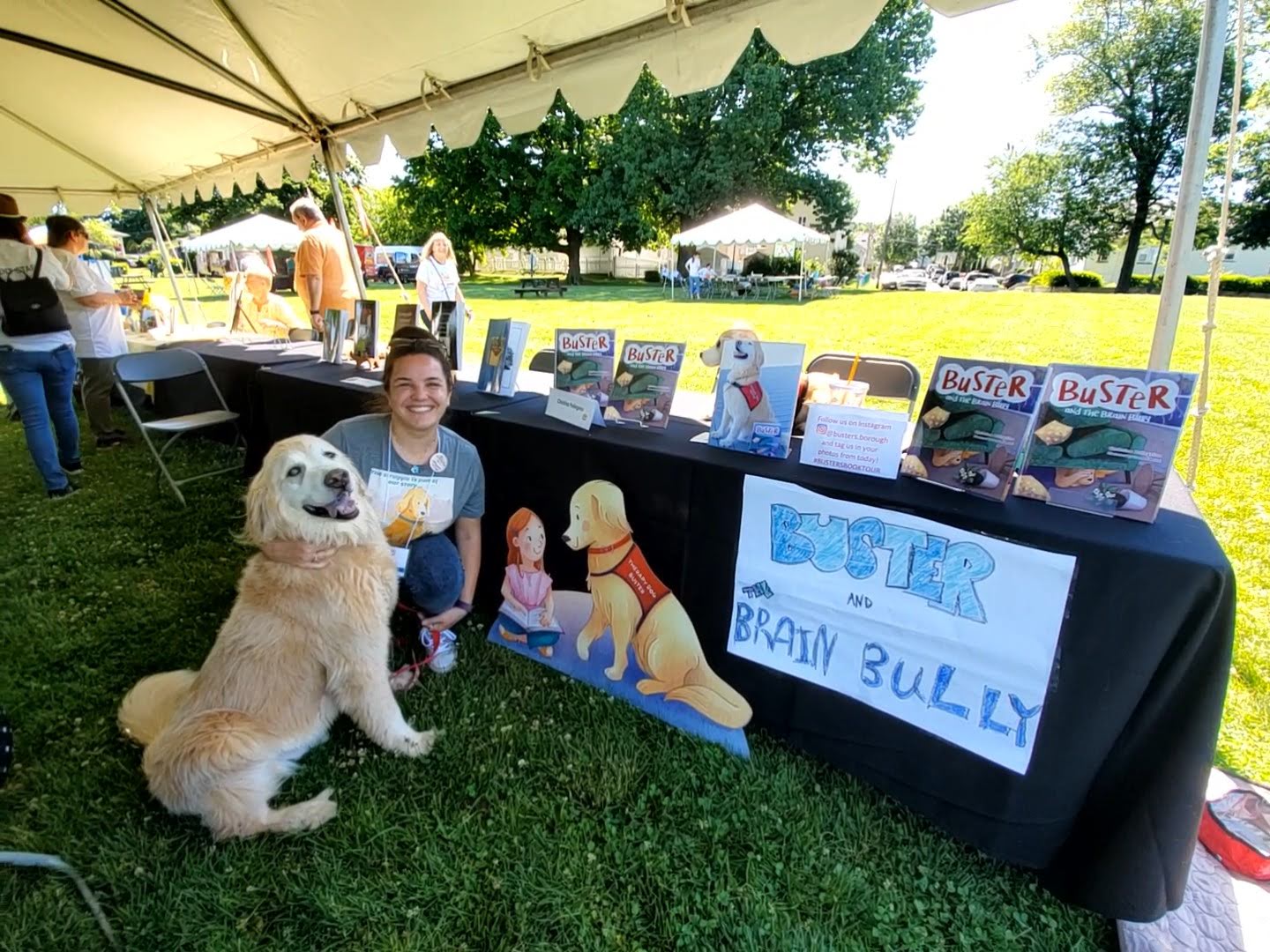 Christina and therapy dog Buster at a book fair selling copies of Buster and the Brain Bully by Christina Pellegrino
