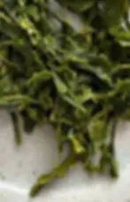 Japanese sencha tea leaves against a blue ceramic background