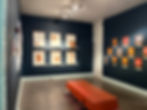 Unabashed Relics art gallery with paintings on dark blue walls
