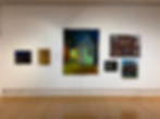 Art gallery wall featuring paintings of houses that watches back.