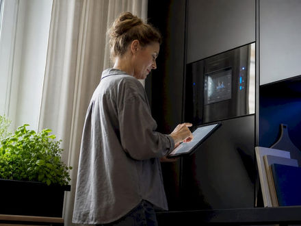 European woman checking smart energy meter with tablet