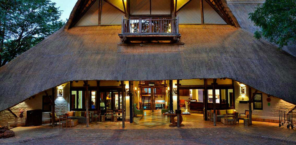 Charming entrance of a thatched-roof lodge, nestled in nature at Victoria Falls safari Lodge.