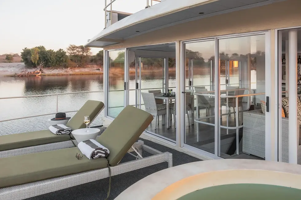 Luxury Chobe Princess houseboat deck with sun loungers, plunge pool, and glass doors overlooking the Chobe River at sunset, Botswana safari experience.