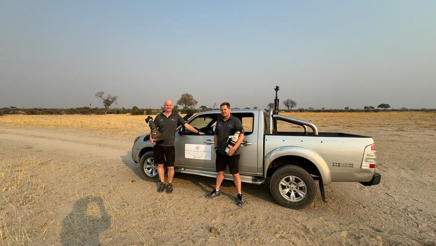 Nick Wigmore & Eric van Staden, co Founders of Photo Safari Company standing infront of their vehicle holding their cameras on a photo safari in Hwange National Park, Zimbabwe.