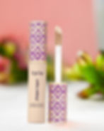 Tarte shape tape concealer displayed with the wand on the right in front, and flowers in soft focus in the background