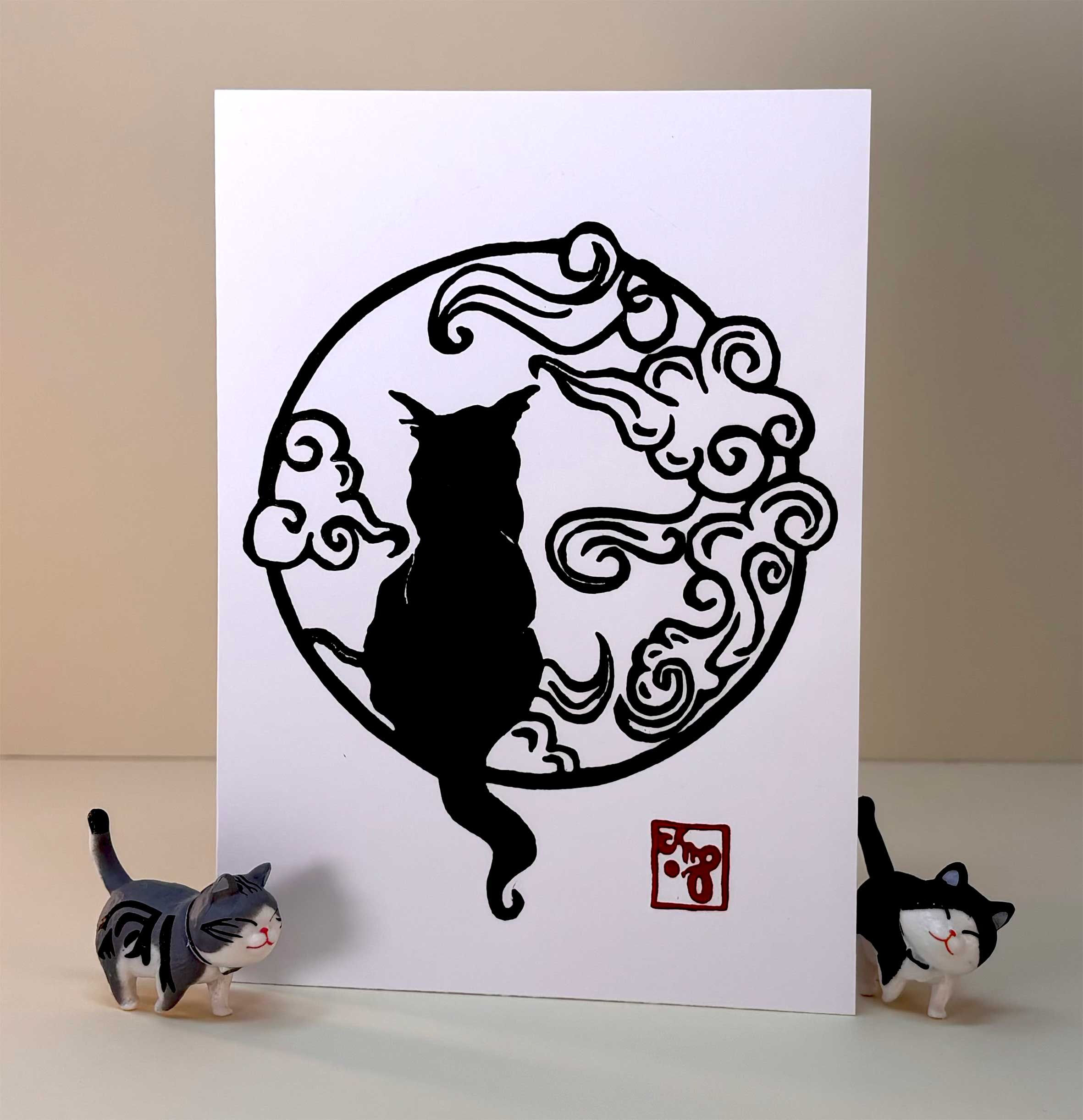 Cat in the clouds greeting card artwork with black ink handprinted on white card paper and white envelope