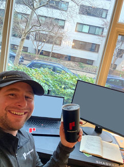man holding coffee cup in front of computers