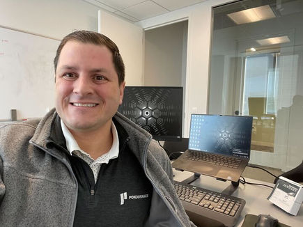 man sitting in office in front of computers and taking selfie