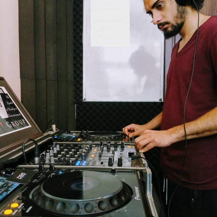 DJ performs at a studio, mixing audio, wearing headphones, DBS DJ'lik ve Prodüksiyon Kursu.