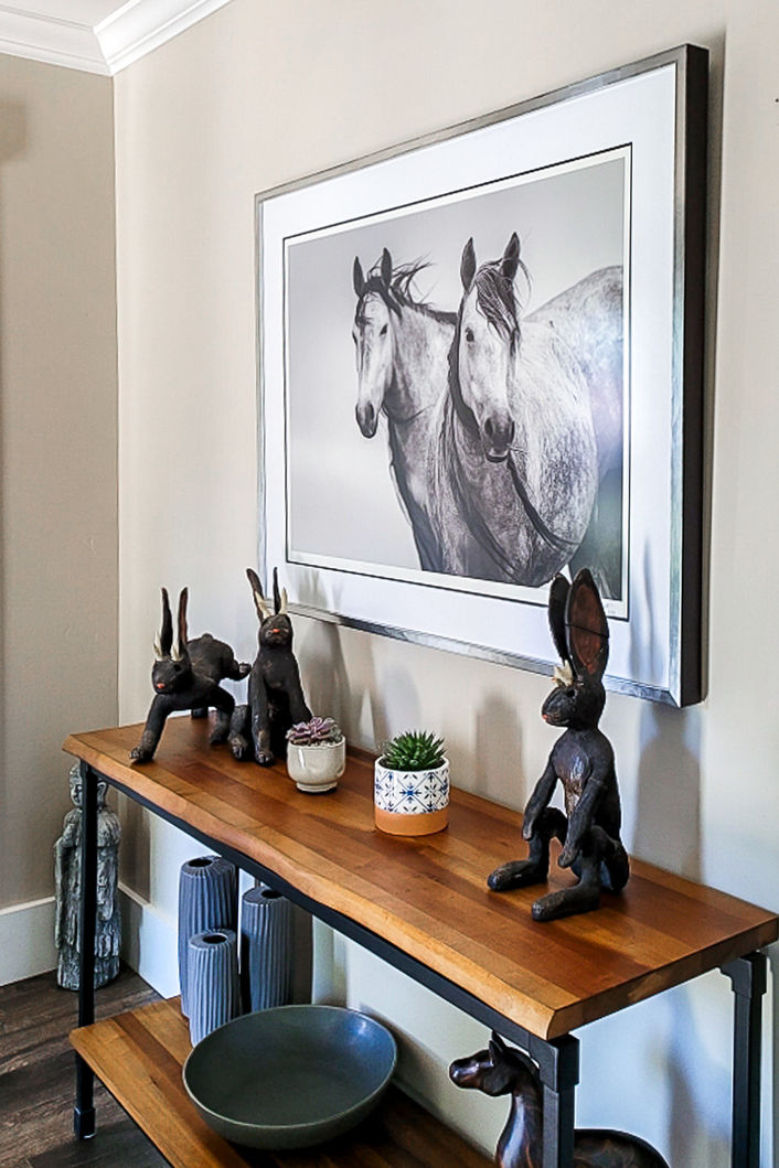 wild horse artwork hanging on a wall over a couch showing two gray wild horses 