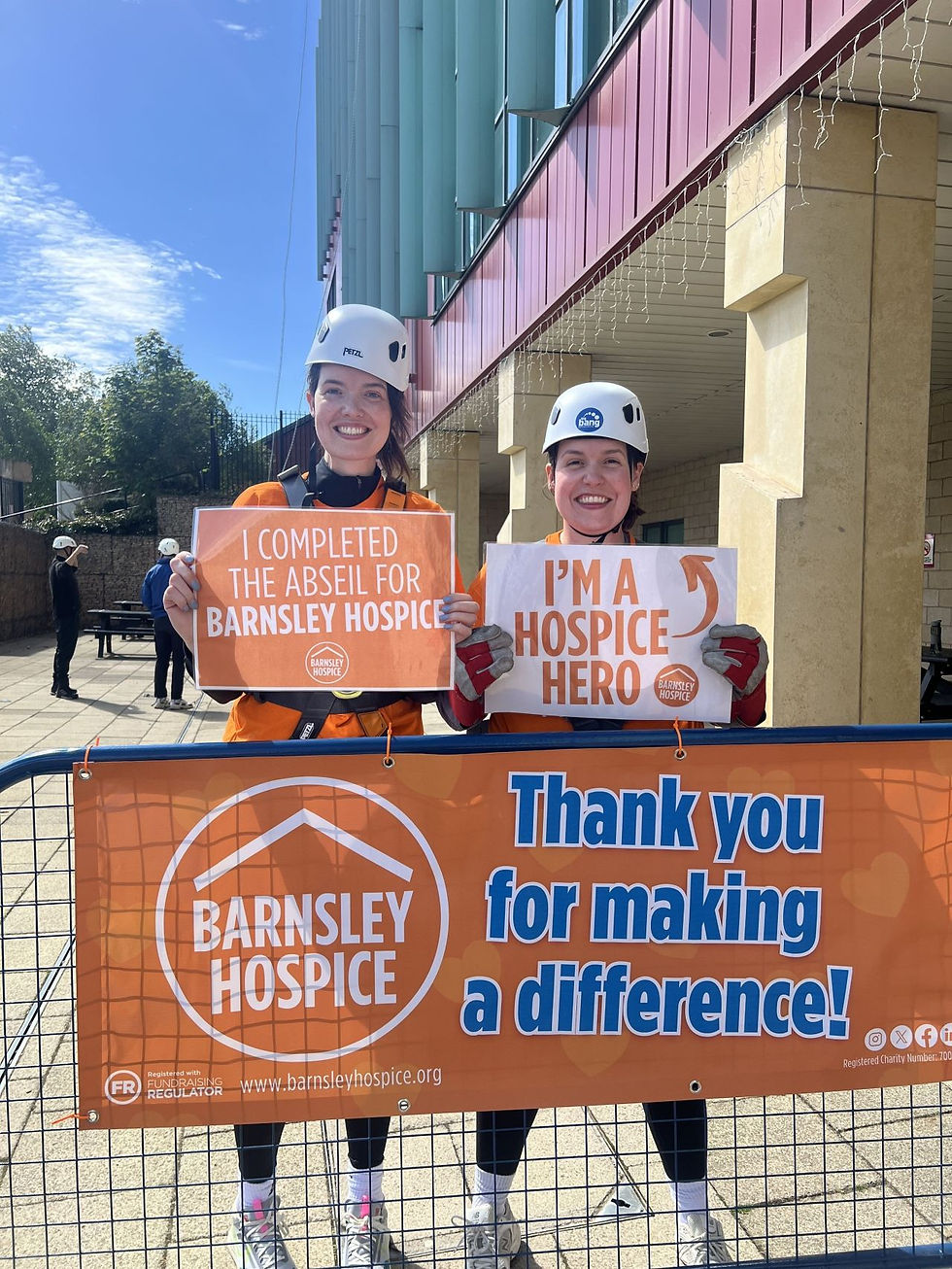 Two fundraisers holding up 'I'm a Hospice Hero' signs after completing a charity abseil for Barnsley Hospice