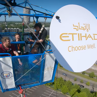 A Man City fan getting ready to jump, with the Etihad logo in the foreground