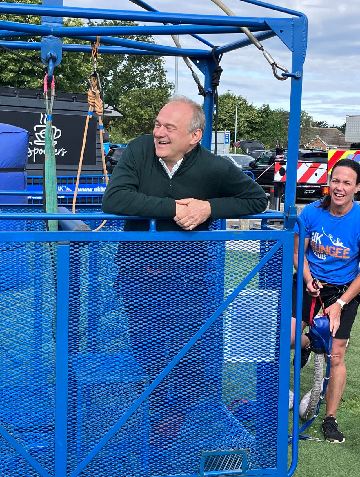 Ed Davey laughing inside the UK Bungee cage, with Cassandra in the background