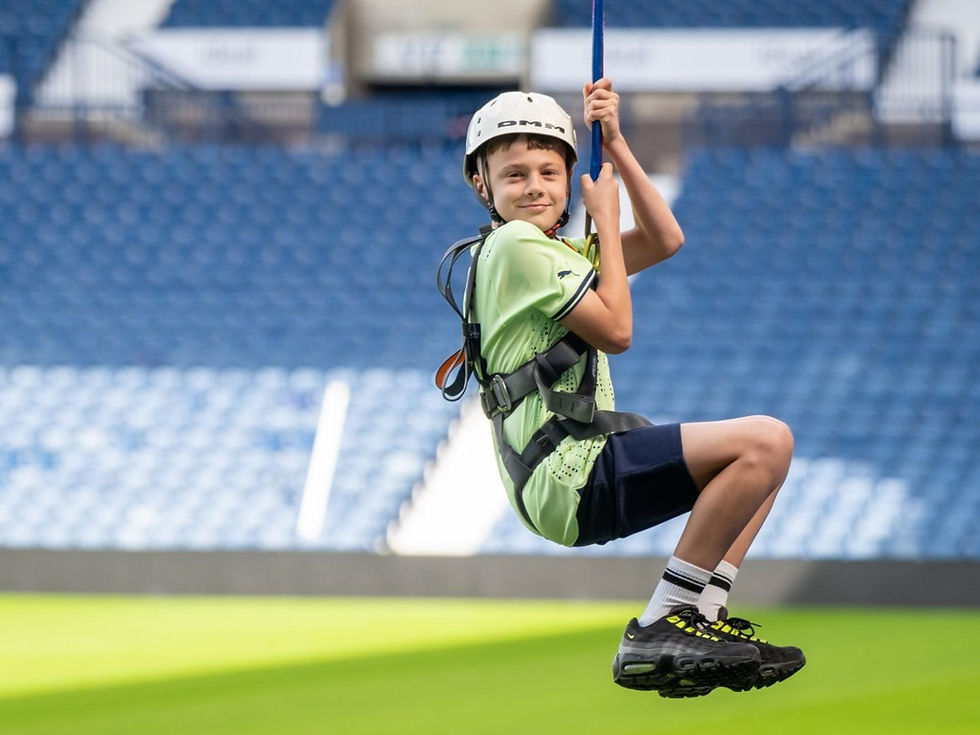 boy smiling as she completes a zip wire through a football stadium