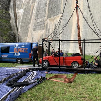 A red car in a specially designed bungee cage, with the UK Bungee Club van in the background