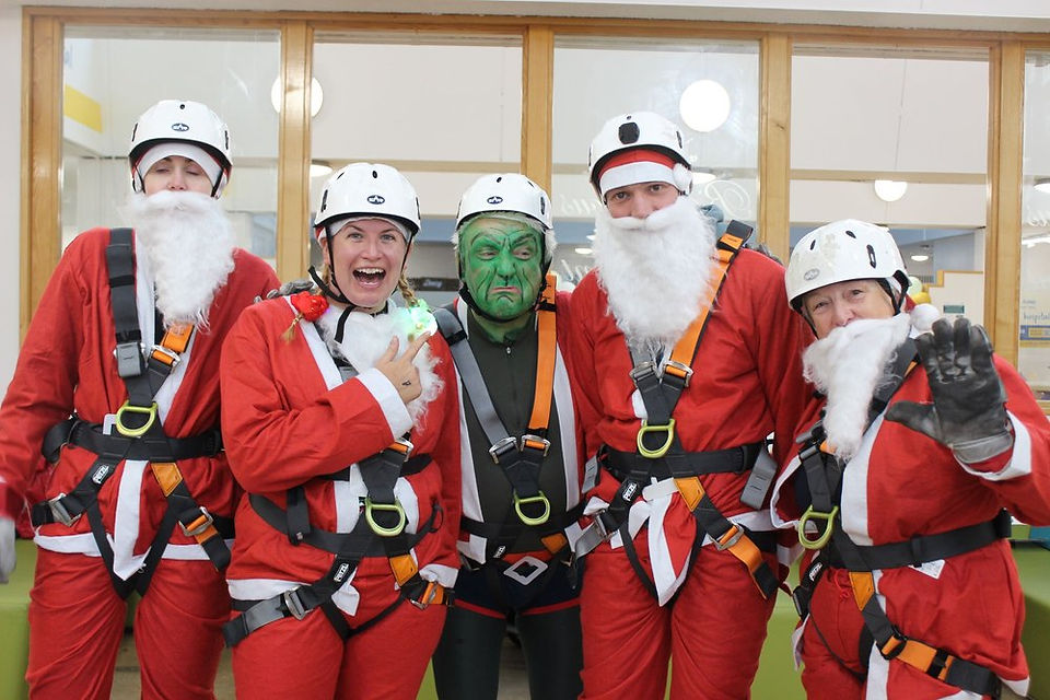 Group of abseilers and a grinch with harnesses and helmets on, ready to abseil