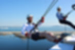 Two abseilers at The Port of Leith Distillery, with sea views stretching out behind them