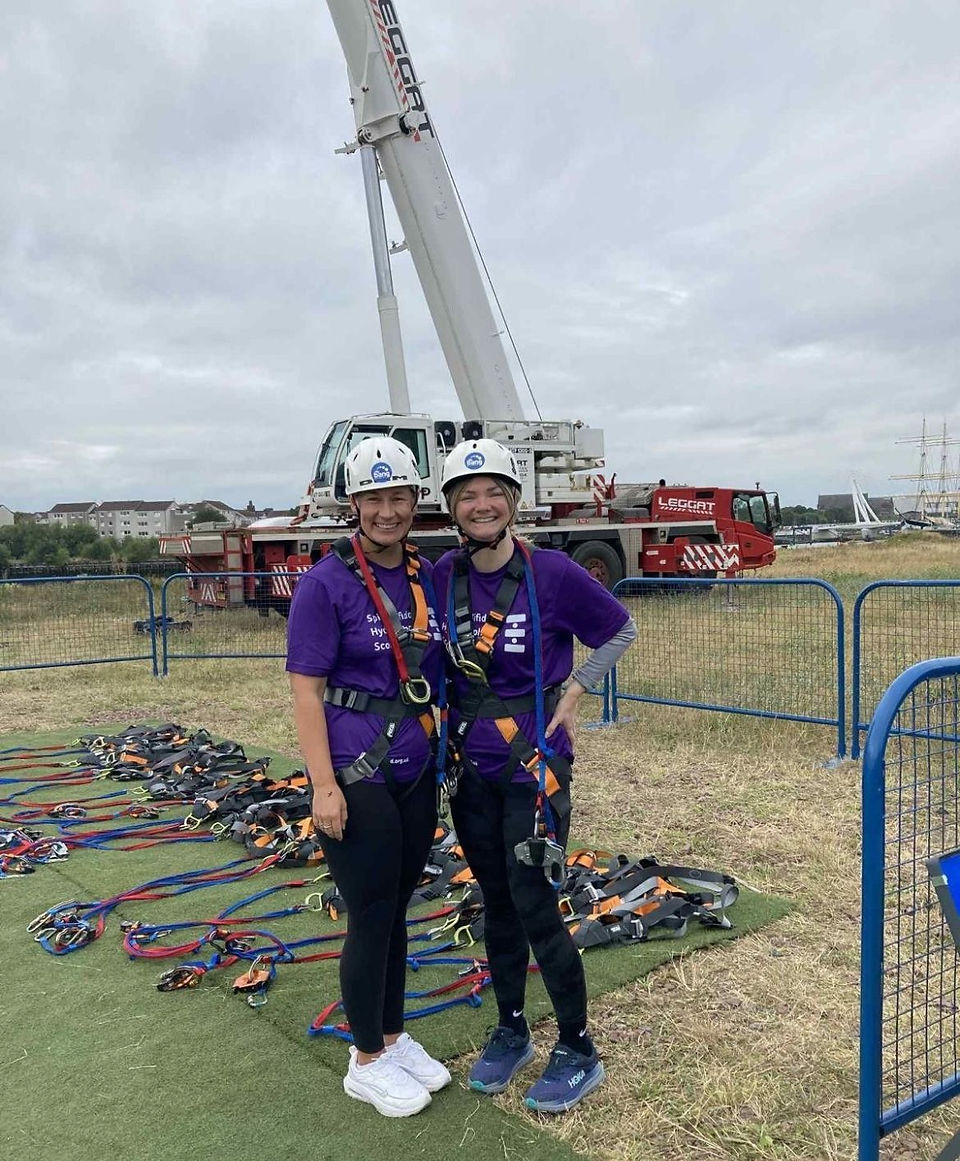 Two supporters harnessed up with helmets on before the zip wire
