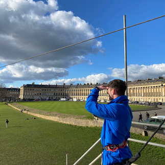 A Big Bang crew member looking down the zipwire, with a view of the Royal Crescent in the background