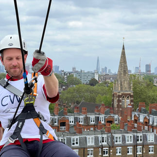 Man abseiling from a building with a view of London in the background