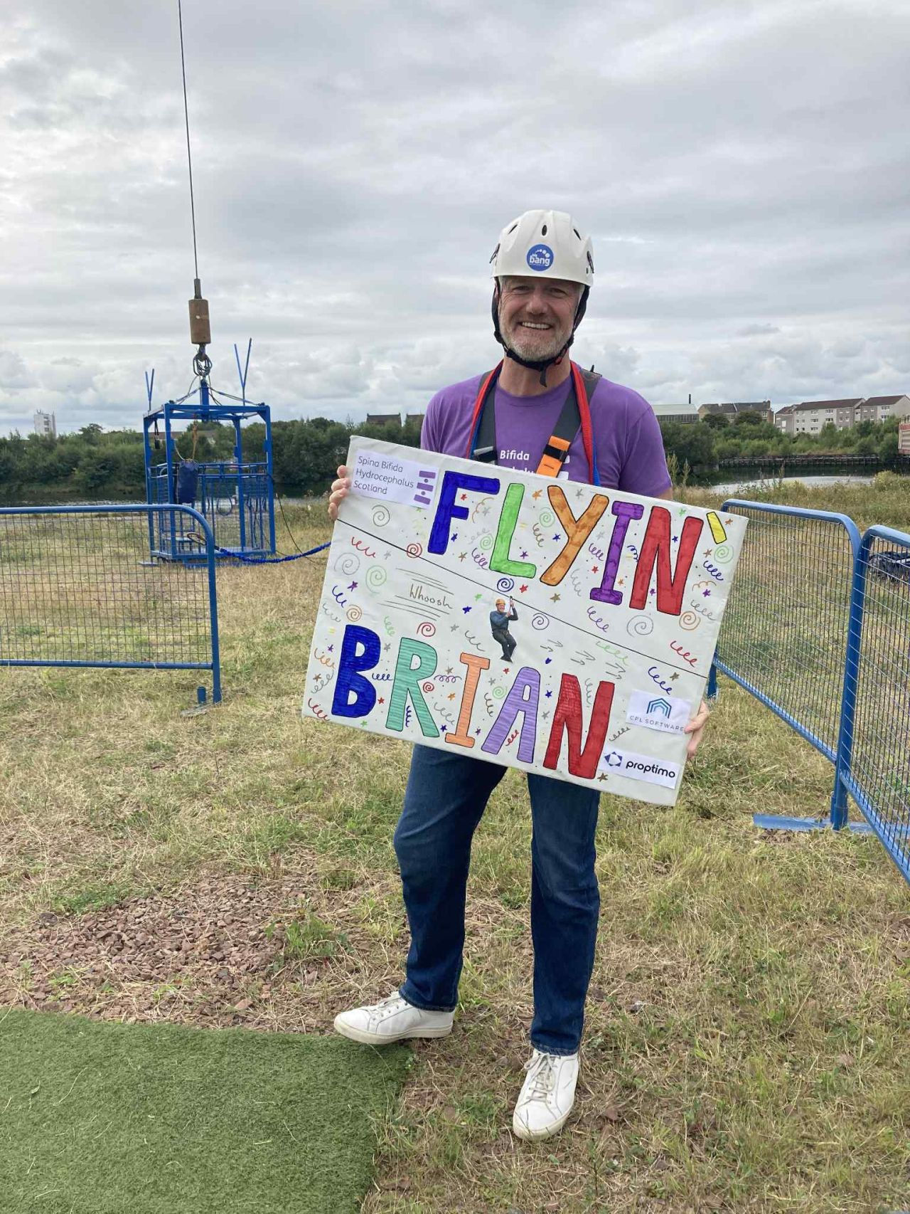 Man holding supportive sign at Zipslide The Clyde 2025