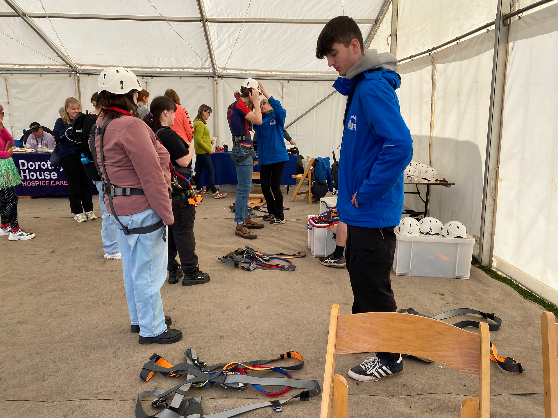 Zipwire participants and Big Bang crew in the harnessing tent, with harnesses and helmets
