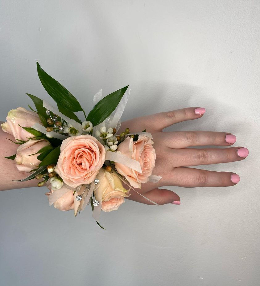 A custom corsage is displayed on a young woman's wrist.  This individual bought her corsage at Walden Floral Design.