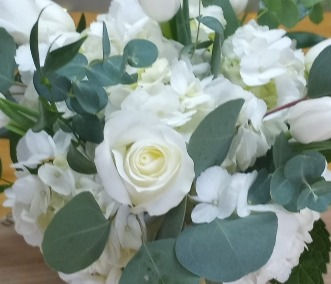 A close-up of the Purely Pearly sympathy flower arrangement showcasing white tulips, hydrangea, roses, and eucalyptus leaves.