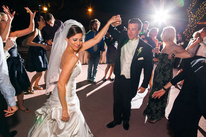 Bride and groom dancing at their wedding reception with guests in the background.