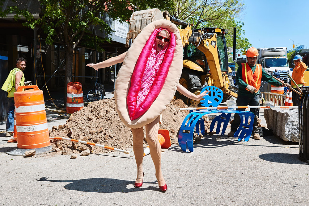 Woman in vulva costume and high heels, happy, at construction site