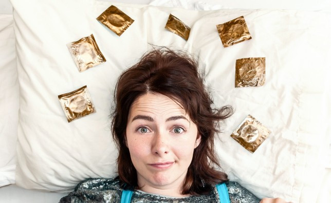 Fran Bushe, smirking, with 6 condoms around her head on a pillow