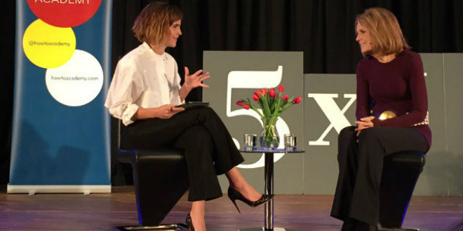 Emma Watson with her hand up talking to Gloria Steinem, both seated and smiling