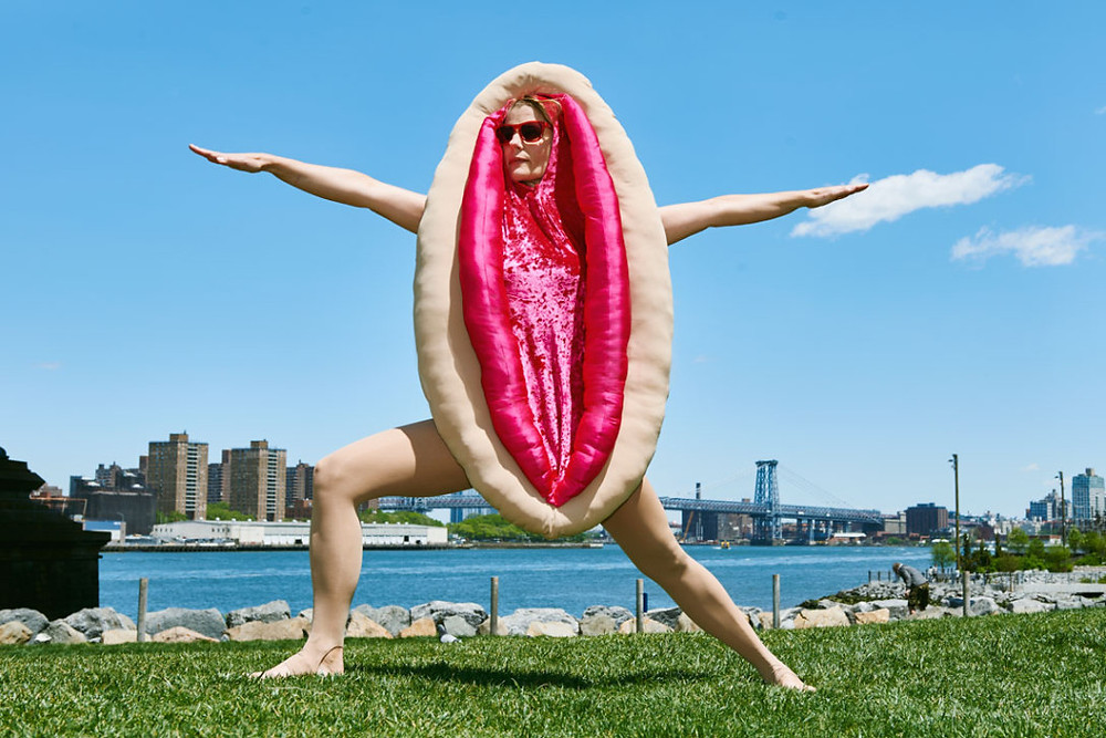 Woman in vulva costume doing yoga outside, arms outstretched