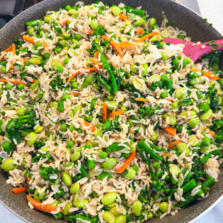 Veggie-loaded orange sesame rice bowl with brown rice, edamame, broccolini, shredded carrots, and peas tossed in a bright citrus sesame sauce.